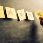 Businessman attaching yellow notes on blackboard with hand drawn stars