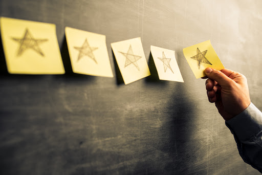 Businessman attaching yellow notes on blackboard with hand drawn stars